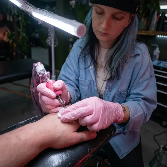 A tattoo artist working on a client's arm